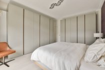 Комфортабельная кровать и минималистский стиль в современной спальне — стоковое фото