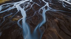 Pintoresca vista aérea de ríos con curvas que fluyen a través de terrenos montañosos salvajes en Islandia - foto de stock