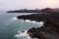 Vue par drone de la mer mousseuse contre la route courbe et les montagnes avec Hervideros à Yaiza Lanzarote Îles Canaries Espagne — Photo de stock