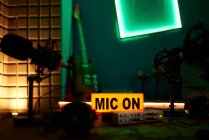 Microfono moderno su treppiede posto sul tavolo in studio buio con illuminazione al neon prima di registrare podcast — Foto stock
