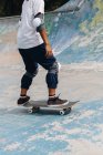 Анонімна молода етнічна особа в повсякденному вбранні в захисних колінних прокладках, що їздять в скейтборді в скейтборді парку — стокове фото
