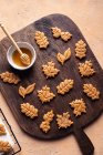 Вид зверху велика кількість листкового солодкого запеченого печива, розміщеного на дерев'яній обробній дошці біля миски меду на кухні — стокове фото