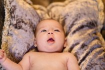 Високий кут чарівного засмученого немовляти плаче, лежачи на м'якій подушці на зручному дивані вдома — стокове фото