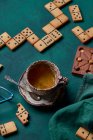 Vue du dessus de délicieux biscuits sucrés en forme de domino placés sur fond vert avec une tasse de boisson chaude et une pâtisserie au chocolat — Photo de stock