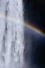 Cenário de tirar o fôlego do arco-íris brilhando sobre a poderosa cachoeira Skogafoss que flui através de penhasco rochoso na Islândia — Fotografia de Stock