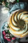 Вид на вкусный лаймовый бисквит, подаваемый на белой тарелке рядом с цветами и ломтиками лайма — стоковое фото