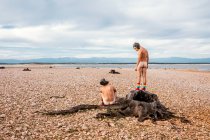 Nackte Männer in Affenmasken schauen in die Kamera, während sie Zeit am steinernen Meeresufer in sonnigen Tagen verbringen — Stockfoto
