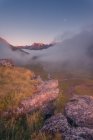 Terreno gramado cercado por montanhas ásperas na natureza da Espanha em tempo nebuloso ao nascer do sol — Fotografia de Stock
