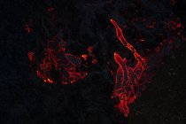 Draufsicht auf glühend rotes Magma, das nachts im Hochland Islands in Dunkelheit auf dunkler bergiger Oberfläche fließt — Stockfoto
