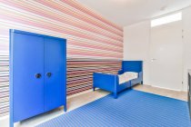 Design creativo della camera da letto con letto tra acquario sul tavolo e parete con ornamento a strisce a casa — Foto stock
