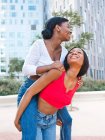 Deliziosa lesbica afroamericana che dà cavalcata al contenuto partner femminile mentre si trova in strada con edifici moderni in città — Foto stock