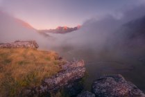Terreno gramado cercado por montanhas ásperas na natureza da Espanha em tempo nebuloso ao nascer do sol — Fotografia de Stock