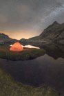 Malerischer Blick auf das Zelt am Seeufer gegen den verschneiten Berg unter wolkenverhangenem Milchstraßenhimmel am Abend im Circo de Gredos Cirque in Spanien — Stockfoto