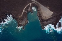 Drone view of foamy sea against curved roadway and mountains with Hervideros in Yaiza Lanzarote Canary Islands Spain — Stock Photo