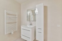 Kreative Gestaltung des Badezimmers mit beheiztem Handtuchhalter gegen Waschtisch mit Wasserhahn unter Spiegel im Leuchtturm — Stockfoto