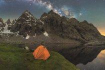 Scenic view of tent on lake shore against snowy mountain under cloudy milky way sky in evening located in Circo de Gredos cirque in Spain — Stock Photo