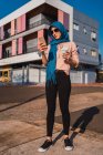 Donna araba alla moda in hijab tradizionale in piedi con caffè per andare in strada e messaggistica sul cellulare nella giornata di sole in città — Foto stock