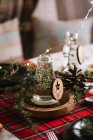 Рождественский стол с венком и декоративными деревянными украшениями и красной клетчатой скатертью с желтыми огнями на заднем плане — стоковое фото