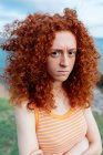 Femme bouleversée avec des cheveux bouclés au gingembre montrant une émotion de mécontentement et regardant la caméra — Photo de stock