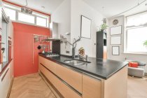Inseltheke mit Unterputzspüle in stilvoller Küche mit verchromten Einbaugeräten in weißem Schrank in heller Wohnung — Stockfoto
