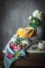 Sabroso pastel de esponja de lima servido en plato blanco cerca de flores y rodajas de lima - foto de stock