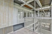 Sala stretta con porta e finestre contro recinzioni in metallo arrugginito sotto il tetto con travi di giorno — Foto stock