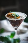 Copo de mousse doce com chocolate e coco decorado com folhas de hortelã e colocado na mesa com plantas verdes — Fotografia de Stock