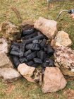 From above of burning charcoal and torch with orange sparks surrounded by rough stones at campsite — Stock Photo
