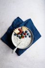Ciotola vista dall'alto di delizioso porridge condito con mirtilli e lamponi vicino a fette di pera servite sul tavolo durante la colazione — Foto stock