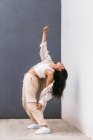 Danzatrice creativa a figura intera in abiti bianchi che danza in strada durante la performance piegandosi all'indietro — Foto stock