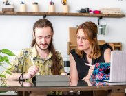 Male and female creative designers drawing sketches on graphic tablets while working together on project in workspace — Stock Photo