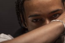 Headshot of serious young African American male with braided hair and bracelet on wrist looking at camera thoughtfully — Stock Photo