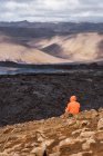 Vista posteriore del turista irriconoscibile che ammira Fagradalsfjall con lava e fumo che si diffonde tra i monti sotto il cielo nuvoloso in Islanda — Foto stock