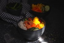 Hohe Winkel der asiatischen Poke mit Lachs und Reis mit verschiedenen Gemüse serviert in Schüssel auf dem Tisch im Restaurant — Stockfoto