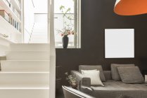 Дизайн интерьера гостиной с удобным диваном и кожаным креслом в современной квартире с белыми и черными стенами — стоковое фото