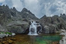 Scenic view of Sierra de Gredos with cascade and pond under cloudy sky — Stock Photo