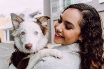 Encantado proprietário do sexo feminino abraçando bonito Border Collie cão e sorrindo com os olhos fechados — Fotografia de Stock