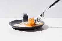 Металлическая вилка со свежим кусочком хлеба, окунутым в жидкий желток жареного яйца, подается на сковороде на белом фоне — стоковое фото
