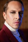 Elegante adulto artista de teatro masculino em casaco de Borgonha e com maquiagem olhando para a câmera com arrogância — Fotografia de Stock