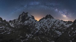 Vista espetacular da galáxia no céu com gás interestelar sobre o monte majestoso áspero com neve à noite — Fotografia de Stock