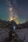 Ефектний вид на високі грубі установки з каскадом і річкою під зоряним небом з галактикою ввечері — стокове фото