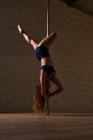 Anmutige, flexible Frau tanzt auf Stange und zeigt Handstand während der Probe im Studio — Stockfoto