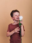 Pondering child in t shirt with plastic light bulb representing idea concept looking up on beige background — Stock Photo
