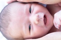 Gros plan de culture anonyme mère toucher la tête de mignon bébé souriant et regardant la caméra — Photo de stock