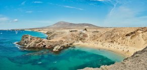 Drone view of sandy beach with tourists located near calm sea with clean turquoise water on sunny summer day in Fuerteventura, Spain — Stock Photo
