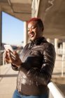 Vista lateral da bela mulher afro se comunicando com seu smartphone — Fotografia de Stock