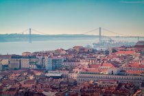 Drone view of red roofed buildings located on coast of Tagus River not far from 25 de Abril Bridge in morning in Lisbon, Portugal — Stock Photo