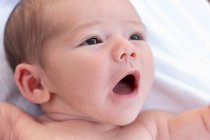 From above adorable naked in infant yawning sweetly while lying on soft bed at home — Stock Photo