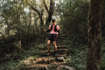 Uomo viaggiatore con bastoni da trekking a piedi su vecchie scale in pietra nella giungla — Foto stock