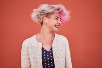 Безтурботний альтернативний жіночий кидання фарбованого короткого волосся на помаранчеву стіну в міській місцевості — стокове фото